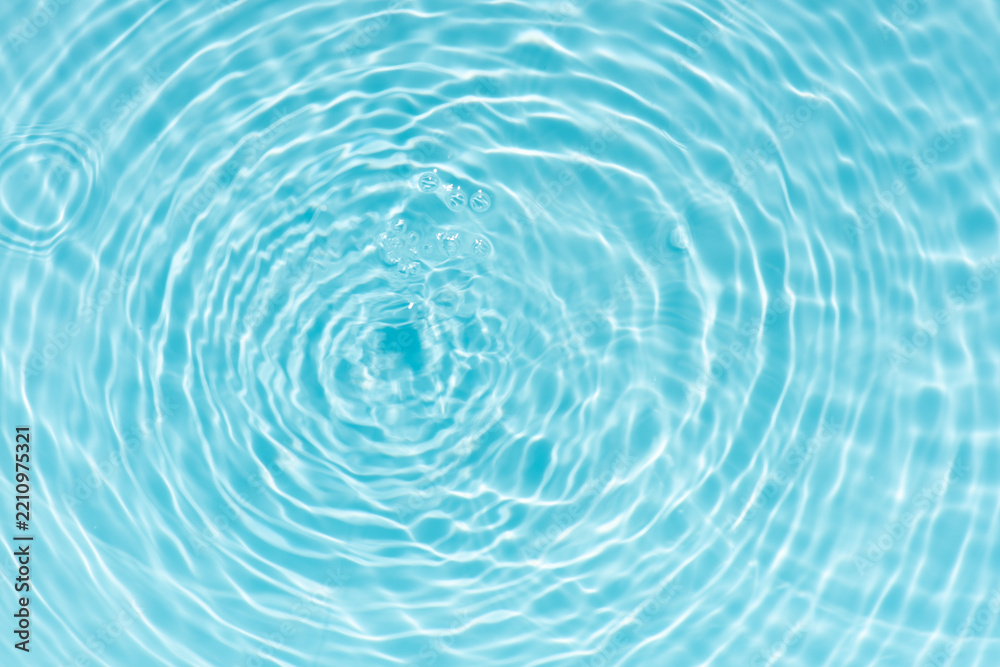 Fototapeta premium Blue water with ripples on the surface. Defocus blurred transparent blue colored clear calm water surface texture with splashes and bubbles. Water waves with shining pattern texture background.