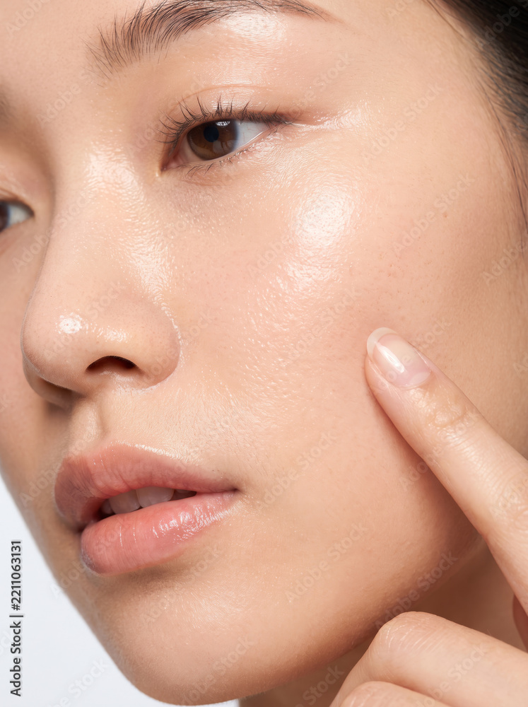 Obraz premium Fresh Asian Beauty Portrait with Woman Gently Touching Her Radiant Cheek
