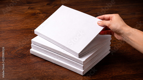 Hand lifting a blank white book or paper stack mockup