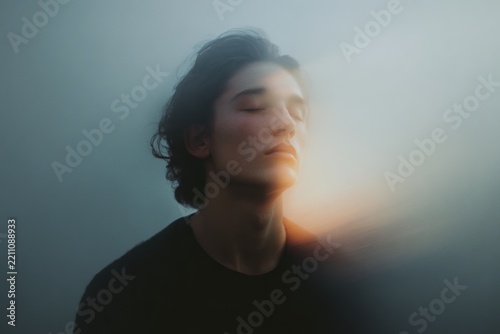 Moody portrait of person with closed eyes and soft lighthouse glow for calm background and meditation poster design