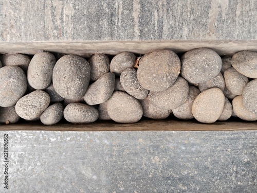 Obraz na plátně A narrow gap or trench running horizontally between floor surfaces, filled with an arrangement of smooth, round and elongated river pebbles of varying sizes