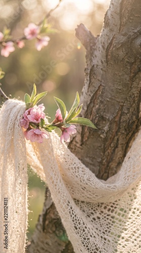 Pink spring blossoms and lace shawl on a sunlit tree trunk