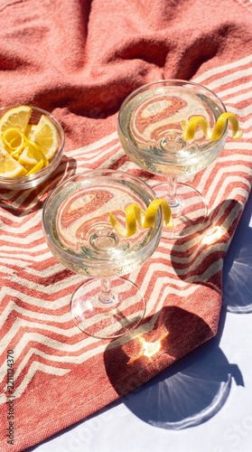 Two glasses of sparkling lemon with raspberries in sunlight