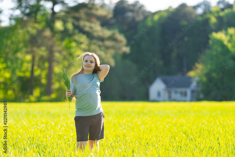 Obraz premium Kid walking through summer grass. Happy kid enjoys rural nature. Kid recreation supports active lifestyle. Kid mood feels cheerful and carefree.