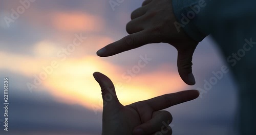 Hands making a picture frame on the sunset seaside