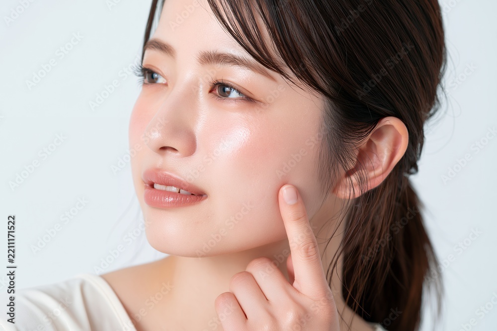 Obraz premium 潤いあふれる透明感のあるツヤ肌を指で触れる若い日本人女性の美容イメージ