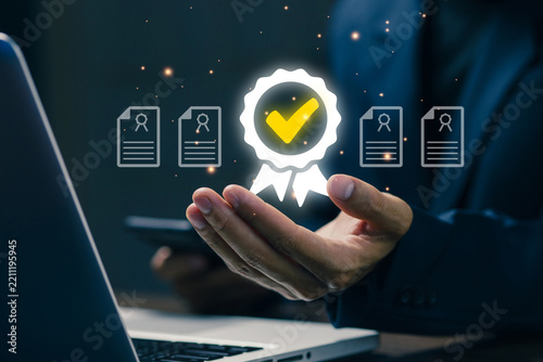 Business professional holding glowing quality certification badge with verified document icons, representing approval, compliance, accreditation, standards, assurance, trust.