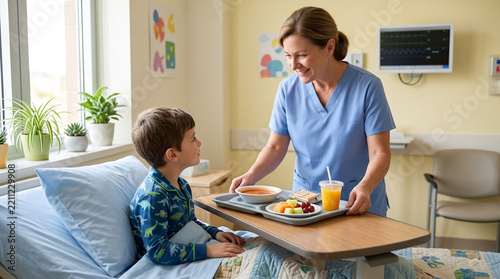 Female nurse bringing meal tray to smiling boy in hospital bed. Healthy food and nutrition for child patient in pediatric ward, lunch time during recovery
