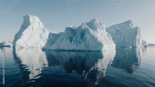 Majestic icebergs floating in calm arctic ocean during daylight with reflections