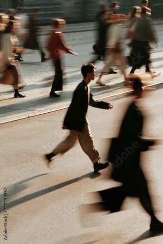 Urban crowd moving rapidly, people walking fast on a city street, motion blur conveying speed and dynamism