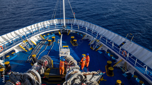 Maritime Workers on the Bow of a Ship Sailing Through Mediterrean sea  Waters, Wearing Safety Gear and Hard Hats
