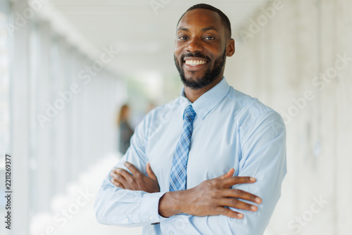 A confident businessman shows a warm smile in a bright office