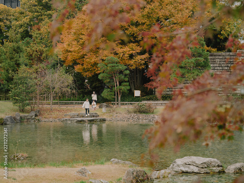 Family on stepping stones surrounded by autumn foliage at a Japanese garden