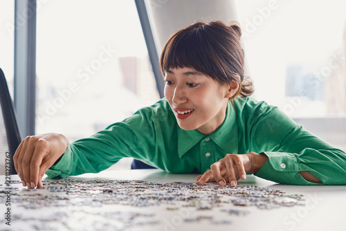 Businesswoman solves a jigsaw puzzle on a table in a London office