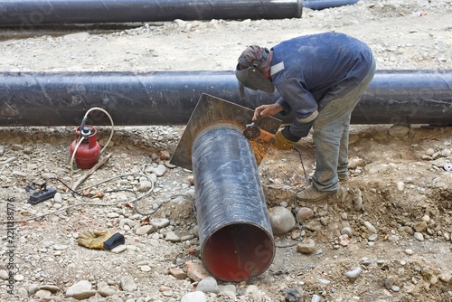 Obraz na plátně Professional laborer using angle grinder tool to cut steel pipe at utility const