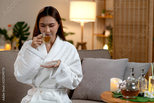 Woman in White Robe Drinking Herbal Tea in Relaxing Spa Lounge
