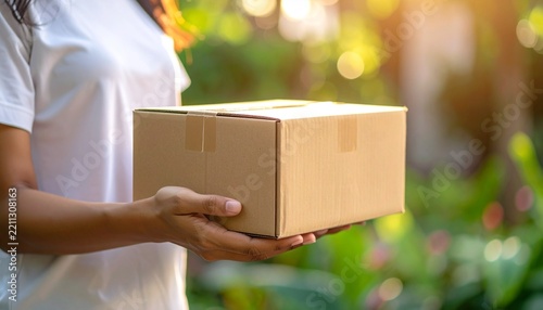 Female Delivery Courier Holding Cardboard Box in Front with Copy Space