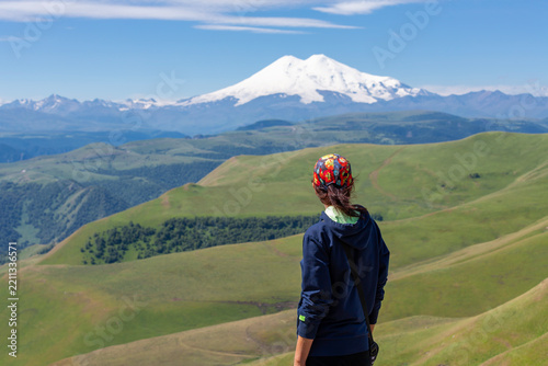 A rear view of a slender, athletic woman admiring the beautiful mountain scenery