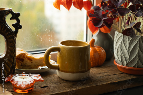 Cozy fall vibes. Mug of tea or coffee on windowsill on autumn day. 
