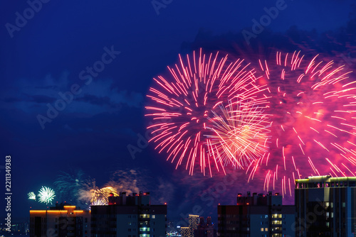 Vibrant big red and gold fireworks display bursting over city buildings in a dark night sky. Ideal for holiday celebrations and urban events
