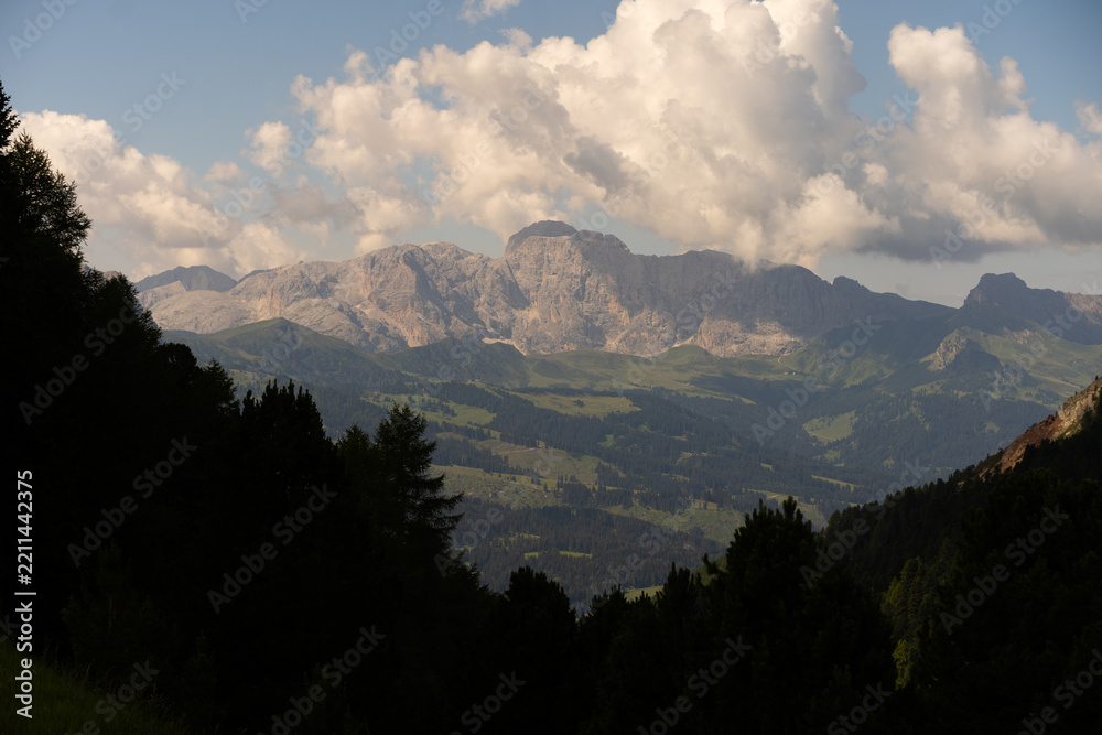 Obraz premium idyllic rolling hills landscape with blooming meadows and alpine mountain peaks in the background on a beautiful sunny day with blue sky and clouds, Alpe di Cisles, Seceda Ridgeline, Dolomiti 