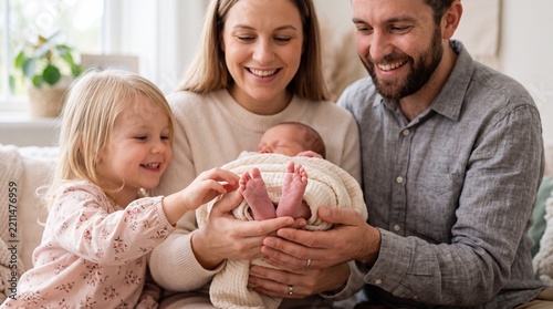 Smiling family of four holding newborn baby at home