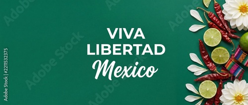 Mexican independence day green background with viva mexico text, fresh limes, red chili peppers, white dahlia flowers, traditional banner layout for viva mexico celebration party card with copy space