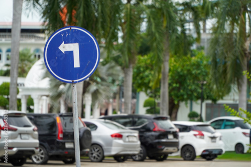 traffic sign indicating a left turn is located to the side of the blurred car.