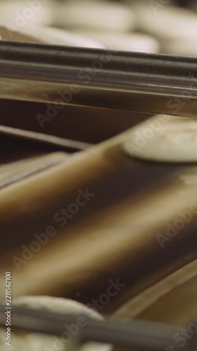 Close up video of pancakes being made on an industrial production line. Food moves along a conveyor belt through an oven. Automated machinery process in a food manufacturing plant