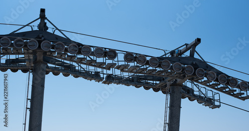 Close-up view of the sheave trains and support towers of a modern cable car system against a clear blue sky