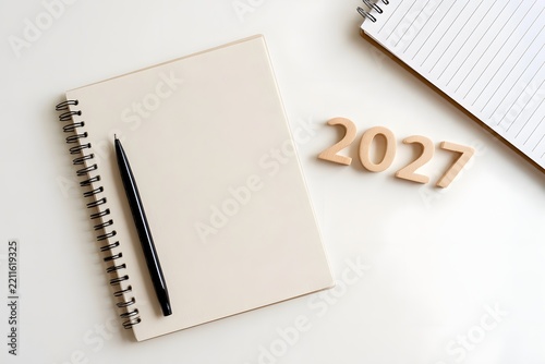 Minimalist desk setup with blank notebook  pen  and wooden numbers spelling 2027 for planning or goal setting