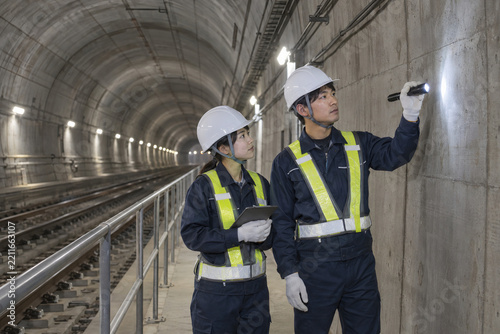 Obraz na płótnie 鉄道トンネルの保守通路で壁面を点検する二人の作業員