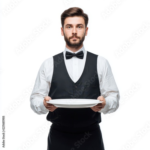 Waiter with Empty Plate: A distinguished waiter, impeccably dressed in a white shirt, black vest, and bowtie, stands ready to serve, holding an empty white plate with a focused gaze.