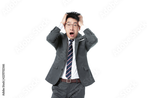 Stressed Asian businessman in suit holding head and shouting on white background
