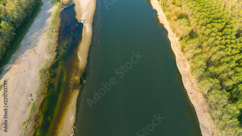 Aerial view of the Po River with low water levels due to drought and summer heatwave, exposing sandy riverbanks and riverbed near Castelvetro Piacentino, Emilia-Romagna, Italy.