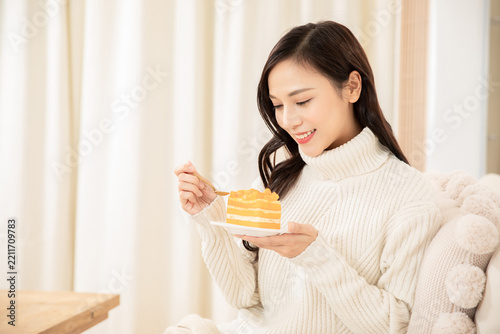 Happy Woman Eating Mango Cake at Home in Cozy Sweater
