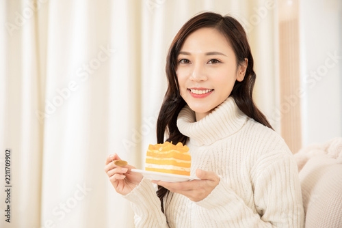 Smiling Woman Holding a Slice of Layered Cake at Home
