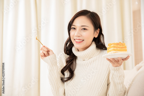 Smiling Asian Woman Holding Mango Cake Slice at Home