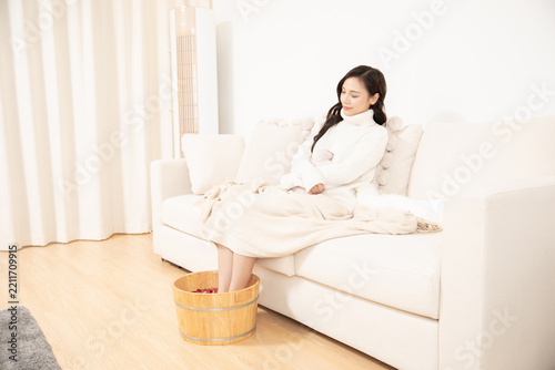 Woman relaxing at home soaking her feet in a wooden bucket for wellness