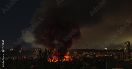 Beautiful dramatic time lapse of a large industrial fire with thick columns of smoke in a city at night
