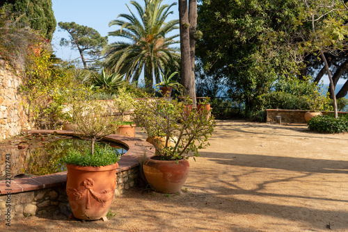 Mediterranean terrace with a small pond and large terracotta pots in Marimurtra Botanical Garden, Blanes, Spain. Scenic coastal garden patio architecture.