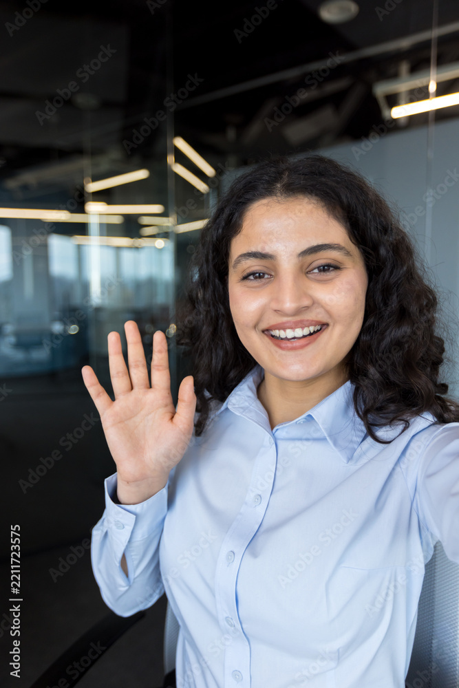 Fototapeta premium Young businesswoman smiling and waving during a video call