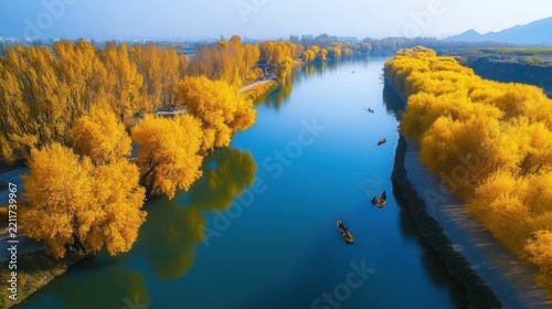 Golden trees line a blue river with people in boats