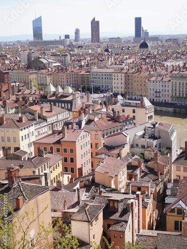 Fotografie Panoramic view over the historic rooftops of Lyon, France, with traditional architecture in the foreground and the modern Part-Dieu business district on the horizon