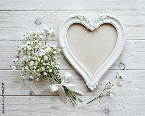 White heart-shaped frame and baby's breath flowers on white wood planks