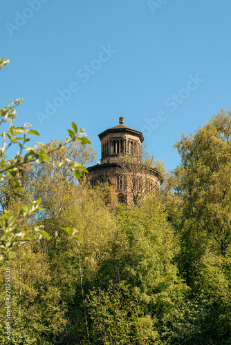 Daylight vertical photograph of the historic Victorian Corstorphine Hill Tower in Edinburgh, Scotland, rising above lush green trees under a clear blue sky