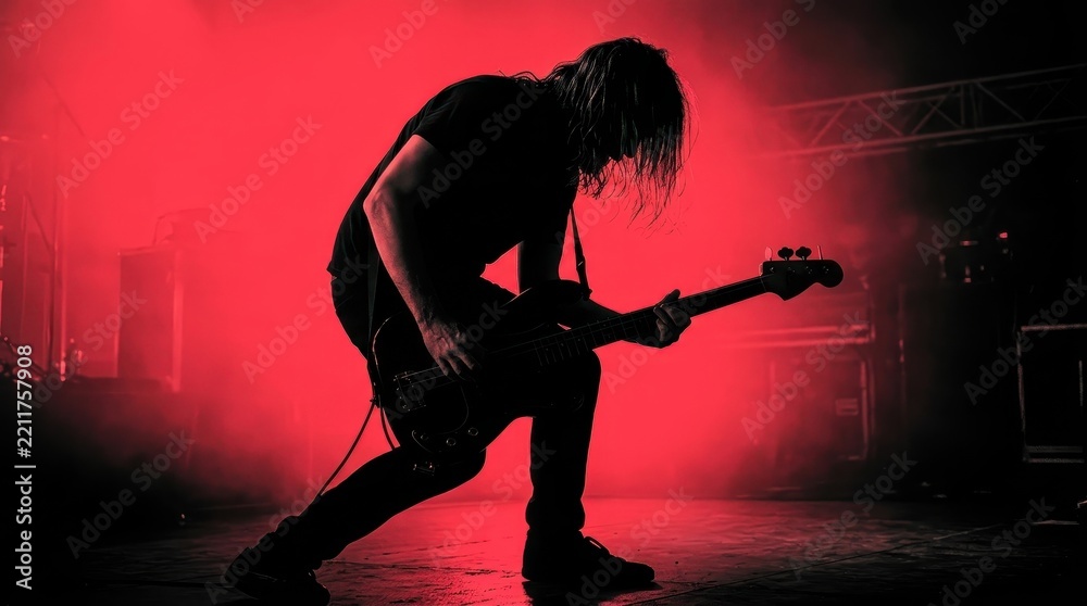 Naklejka premium Silhouette of a Rock Bassist Performing on Stage with Intense Red Lighting and Smoke Effects at a Live Concert