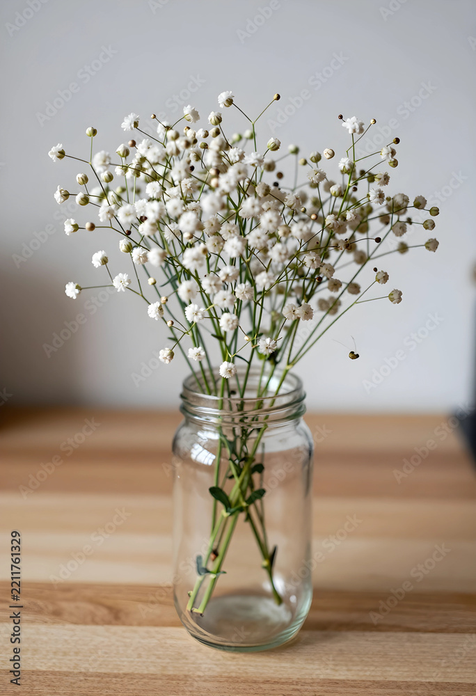 Fototapeta premium Minimalist home decor and wellness, babys breath flowers in a glass jar on a wooden table for interior design and simple lifestyle aesthetic