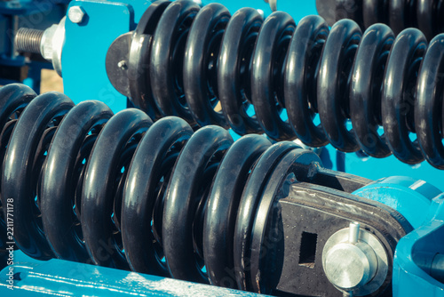 Steel black spring as part of heavy agricultural, industrial machine. Technology