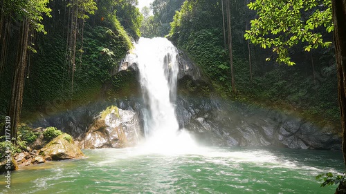 Tropical waterfall cascade flowing into natural green pool in lush jungle forest